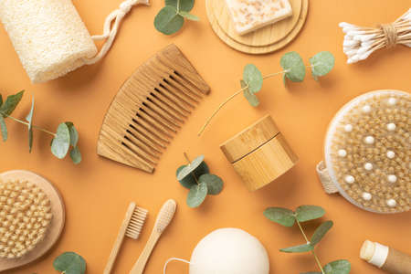 Top view photo of spa accessories anti-cellulite washcloth wooden hair brush bottle and tube with cosmetics soap on wooden stand cotton buds toothbrushes and eucalyptus on isolated beige backgroundの写真素材