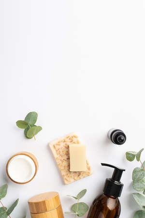 Top view vertical photo of glass bottles cream jar organic soap and eucalyptus on isolated white background with copyspaceの写真素材