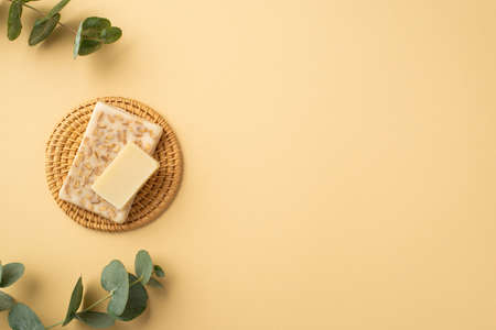 Top view photo of eucalyptus and soap on wicker stand on isolated pastel beige background with copyspaceの写真素材