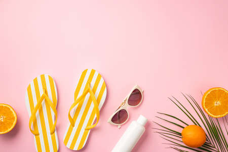 Summer holidays concept. Top view photo of sunglasses striped yellow slippers sunscreen bottle juicy...