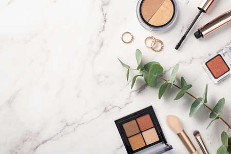Make-up concept. Top view photo of eyeshadow and contouring palettes mascara gold rings makeup...