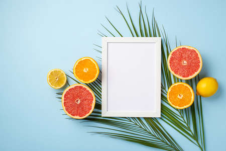 Summer vacation concept. Top view photo of white photo frame tropical fruits cut lemons oranges...