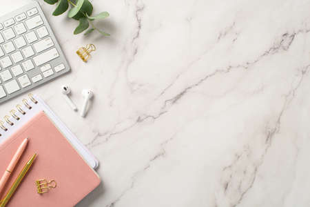 business concept. Top view photo of workplace keyboard pink notepads wireless earbuds pens gold...