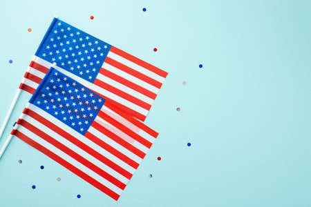 USA Independence Day concept. Top view photo of two national flags and confetti on isolated pastel...