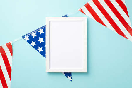 USA Independence Day concept. Top view photo of photo frame and national flag garland on isolated pastel blue background with empty spaceの写真素材