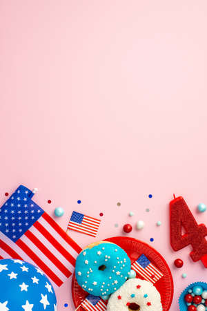 Fourth of July concept. Top view vertical photo of US national flags number 4 candle paper molds with sweets plate with donuts balloon and confetti on isolated pastel pink background with copyspaceの写真素材