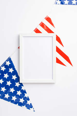 Fourth of July concept. Top view vertical photo of photo frame and national flag garland on isolated white background with empty spaceの写真素材
