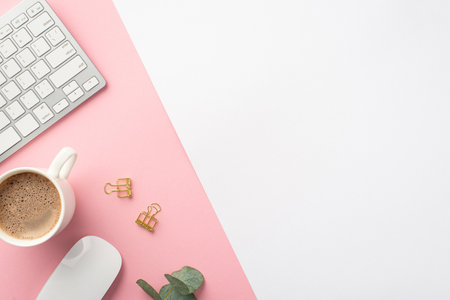business concept. Top view photo of workstation keyboard computer mouse gold binder clips eucalyptus and cup of coffee on bicolor pink and white background with copyspaceの写真素材