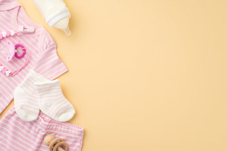 baby clothing concept. Top view photo of pink shirt panties socks pacifier chain bottle and wooden rattle on isolated pastel beige background with copyspaceの写真素材