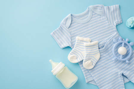 baby accessories concept. Top view photo of blue infant clothes socks shirt panties milk bottle rattle and pacifier on isolated pastel blue backgroundの写真素材