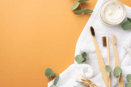 Top view photo of toothbrushes jar with toothpaste cotton buds white towel and eucalyptus on isolated beige background with copyspaceの写真素材