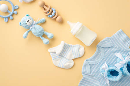 baby accessories concept. Top view vertical photo of blue shirt knitted booties milk bottle socks...
