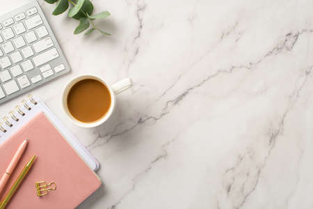 business concept. Top view photo of workspace keyboard pink reminders cup of coffee pens gold binder clip and eucalyptus on white marble background with copyspaceの写真素材
