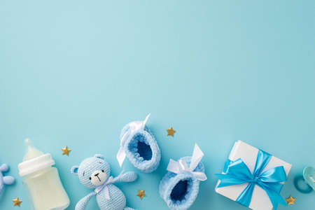 baby accessories concept. Top view photo of giftbox knitted booties teddy-bear toy pacifier milk...