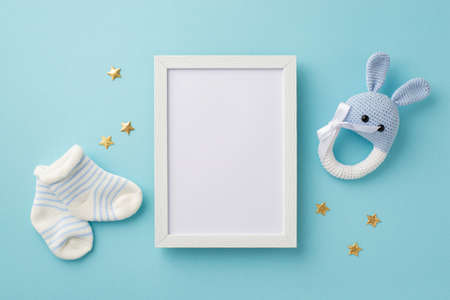 baby accessories concept. Top view photo of photo frame tiny socks knitted bunny rattle toy and gold...