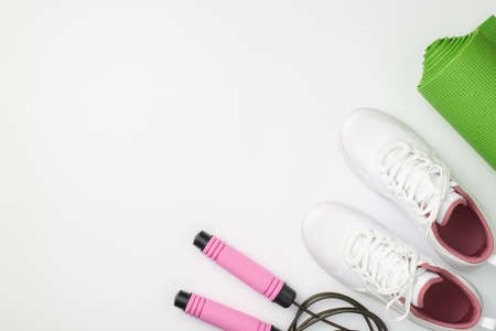 Active lifestyle concept. Top view photo of white sneakers green sports mat and skipping rope on isolated white background with copyspaceの写真素材