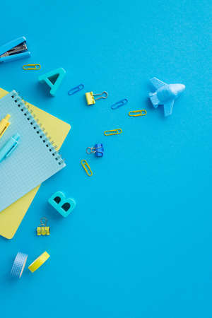 Back to school concept. Top view vertical photo of airplane carries school accessories binder clips...