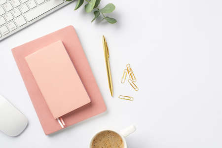 business concept. Top view photo of workspace keyboard computer mouse pink planners cup of coffee clips gold pen and eucalyptus sprig on isolated white backgroundの写真素材