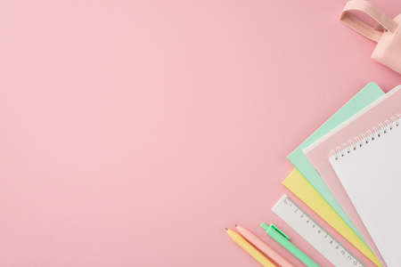 Back to school concept. Top view photo of colorful stationery stack of copybooks pens ruler and pink pencil-case on isolated pink background with empty spaceの写真素材