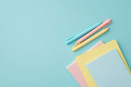 school supplies concept. Top view photo of colorful stationery pens and copybooks on isolated pastel...
