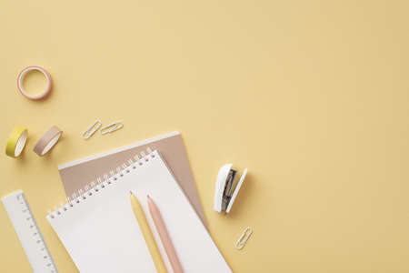 school accessories concept. Top view photo of stationery copybooks ruler pens clips stapler and adhesive tape on isolated pastel yellow backgroundの写真素材
