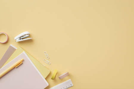 Back to school concept. Top view photo of stationery diaries pen ruler clips mini stapler and adhesive tape on isolated pastel yellow background with copyspaceの写真素材