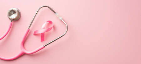 breast cancer awareness concept. Top view photo of stethoscope and pink silk ribbon on isolated pastel pink background with copyspaceの写真素材