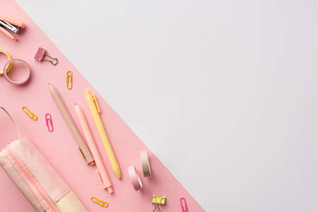 school accessories concept. Top view photo of pink and yellow stationery pens mini stapler binder clips adhesive tape and pencil-case on bicolor pink and white background with copyspaceの写真素材