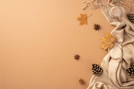Autumn inspiration concept. Top view photo of yellow maple leaves candle anise pine cones and plaid on isolated beige background with copyspaceの写真素材