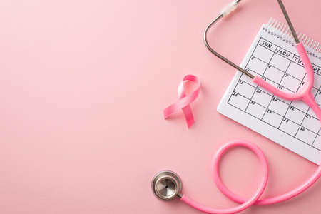 breast cancer awareness concept. Top view photo of pink silk ribbon stethoscope and calendar on isolated pastel pink background with copyspaceの写真素材