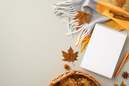 autumn aesthetic concept. Top view photo of open notebook pen wicker basket with cookies plaid cinnamon sticks fallen maple leaves and anise on isolated gray backgroundの写真素材