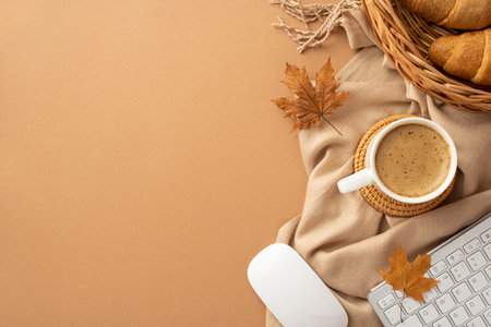Autumn business concept. Top view photo of cup of coffee rattan placemat wicker tray with croissants computer mouse keyboard yellow maple leaves and scarf on isolated beige background with copyspaceの写真素材