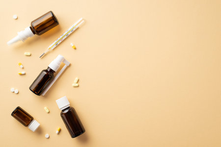 disease concept. Top view photo of remedy transparent brown bottles pills capsules and thermometer on isolated beige background with empty spaceの写真素材