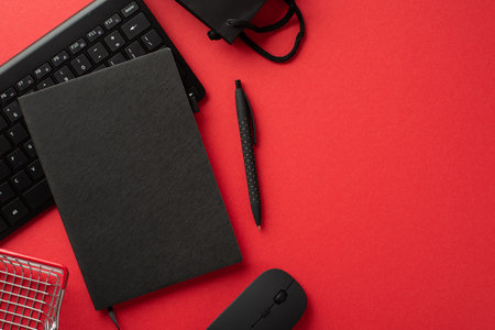 Black friday concept. Top view photo of black planner pen computer mouse keyboard paper bag and shopping cart on isolated red background with copyspaceの写真素材