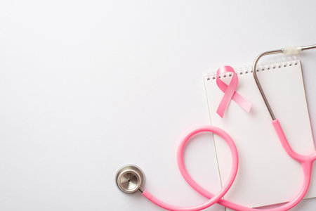 breast cancer awareness concept. Top view photo of pink silk ribbon stethoscope and notebook on isolated white backgroundの写真素材