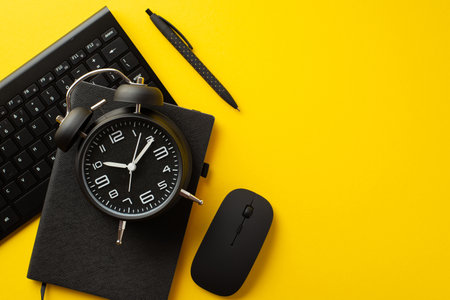 Black friday sales concept. Top view photo of black alarm clock reminder pen computer mouse and keyboard on isolated yellow backgroundの写真素材