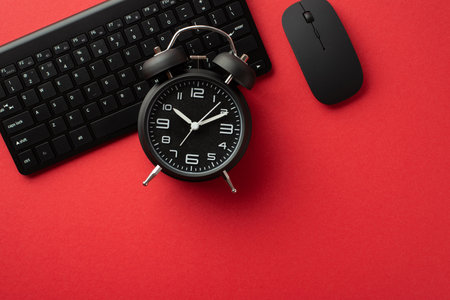 Black friday concept. Top view photo of black alarm clock computer mouse and keyboard on isolated red background with empty spaceの写真素材