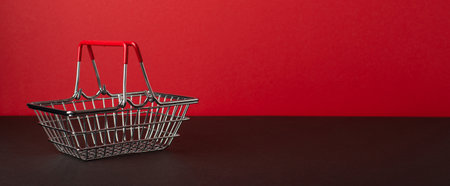 Black friday sales concept. Photo of empty shopping cart on black tabletop red wall background with copyspaceの写真素材