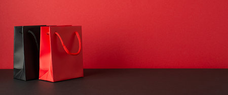 Black friday sales concept. Photo of red and black paper bags on black desktop red wall background with empty spaceの写真素材