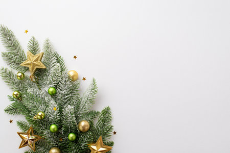 New year concept. Top view photo of pine branch with gold and green baubles gold star ornaments and shiny confetti on isolated white background with empty spaceの写真素材