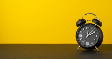 Black friday sales concept. Photo of black alarm clock on desktop yellow wall background with empty...