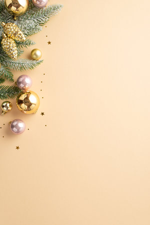 Christmas tree decoration concept. Top view vertical photo of gold and pink baubles pine cone ornaments fir branch in hoarfrost and shiny confetti on isolated pastel beige background with empty spaceの写真素材