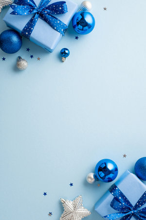 New year concept. Top view vertical photo of big present boxes with ribbon bows blue silver baubles glowing star ornament and confetti on isolated pastel blue background with empty spaceの写真素材