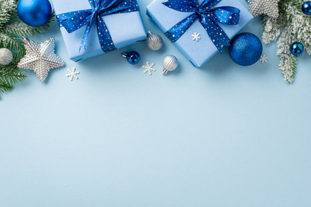 christmas concept. Top view photo of trendy gift boxes with bows blue and silver baubles sparkle star ornaments pine branches in snow and confetti on isolated pastel blue background with copyspaceの写真素材
