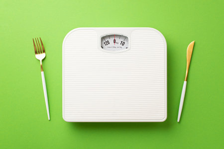 weight loss concept. Top view photo of cutlery fork knife and scales on isolated green background