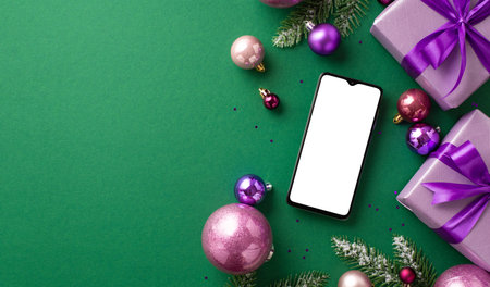 New Year celebration concept. Top view photo of smartphone lilac gift boxes with bows violet and pink baubles fir branches in snow and purple sequins on isolated green background with empty spaceの写真素材