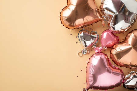 Top view photo of Valentine's Day decorations stylish heart shaped balloons and silver sequins on isolated light beige background with empty spaceの写真素材