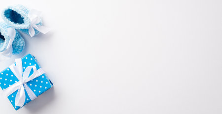 baby boy concept. Top view photo of blue knitted booties and giftbox with bow on isolated white background with copyspaceの写真素材