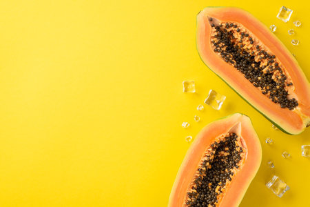 Sunny tropical concept. Top above view photo of papaya slices with ice cubes isolated on bright yellow backdrop with empty spaceの写真素材