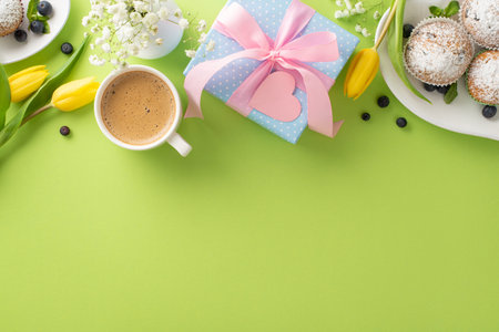 Happy mother's day minimalistic celebration concept. Top view flat lay of plates with cupcakes, gift boxes, and tulips on green background with empty space for text or greeting messageの写真素材
